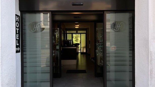 A hotel entrance with a reception desk, a coffee machine, and a view of the interior. - Hotel Salerno (Milan)
