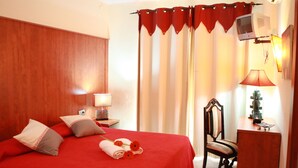 A hotel room with a bed, a chair, a desk, a lamp, and curtains. - Hotel los Globos (Sitges)