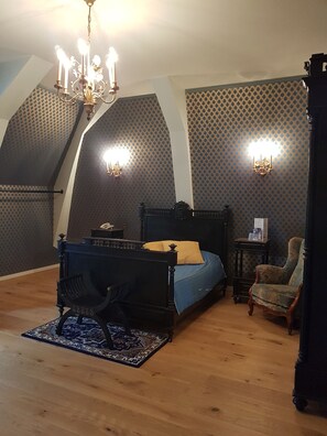 A bedroom with a four-poster bed, a chandelier, patterned wallpaper, and a wooden floor. - Château de la Tremblaye (Cholet)