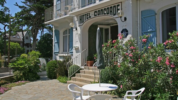 A hotel with a balcony, outdoor seating, and a stone pathway.