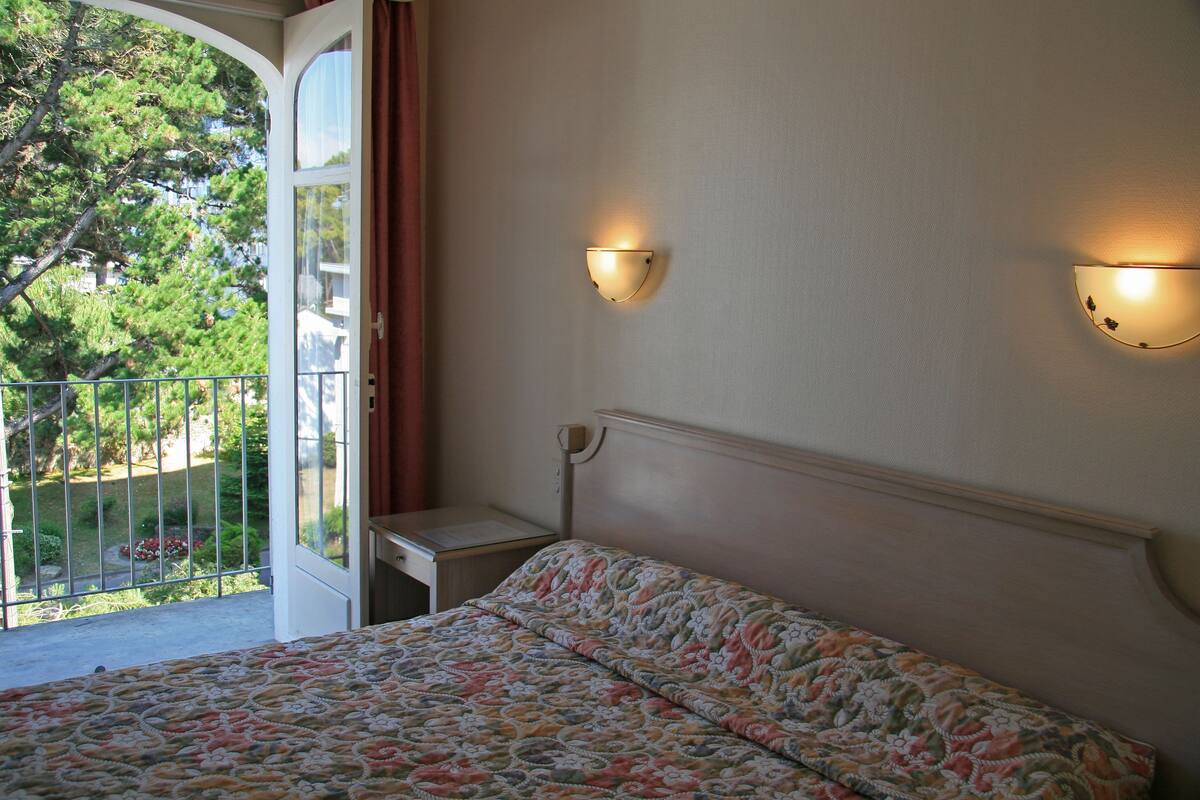 Un dormitorio con una cama, una mesita de noche y dos luces fijadas a la pared.