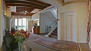 A spacious foyer with a wooden ceiling, a staircase, and a reception desk.