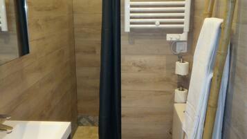 Een badkamer met een douche, toilet en wastafel.