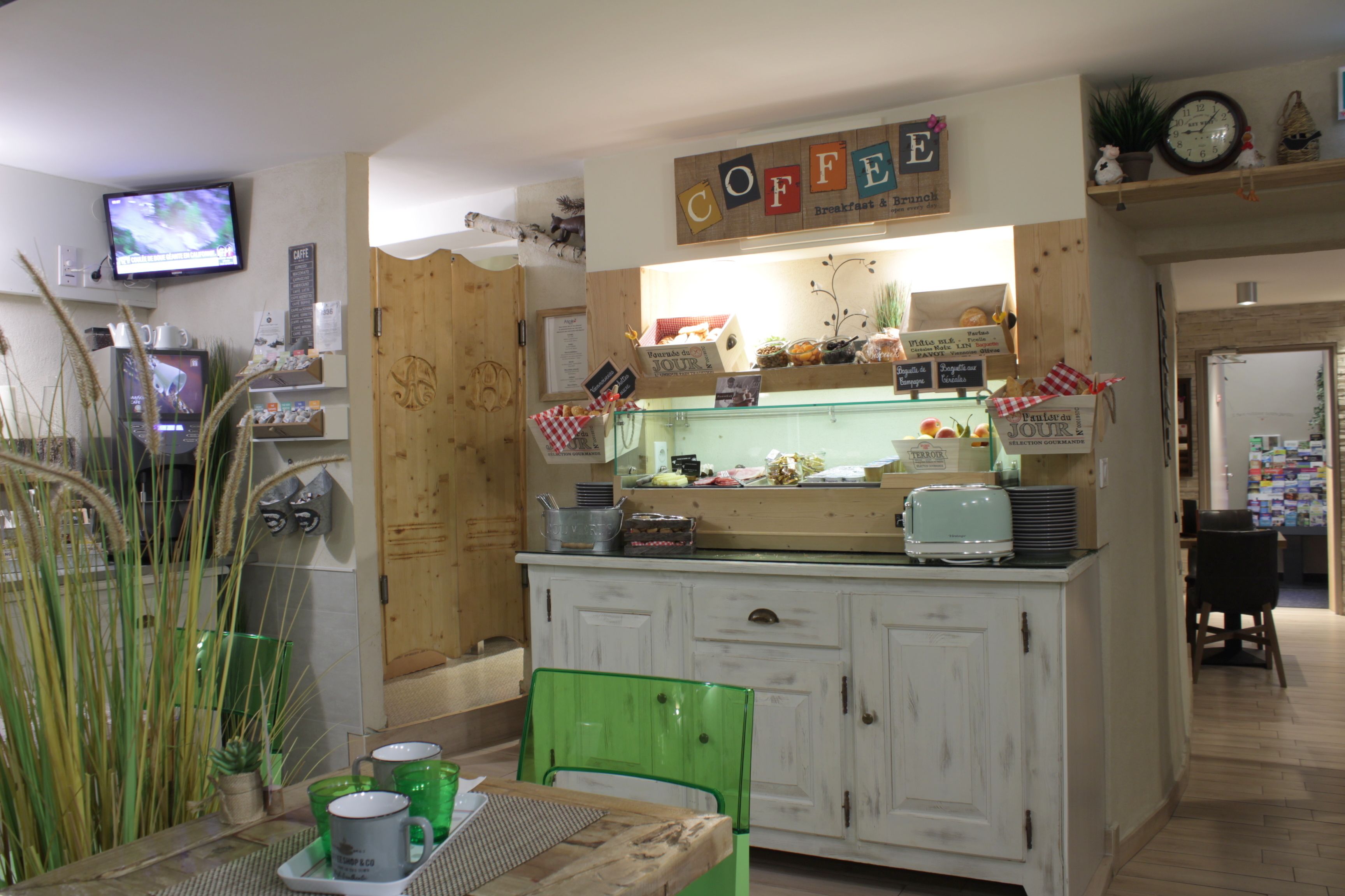 A café with a wooden counter, a television, and various food items displayed.