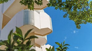 Ein modernes Gebäude mit einem einzigartigen architektonischen Design, mehreren Balkonen und blauem Himmel im Hintergrund.