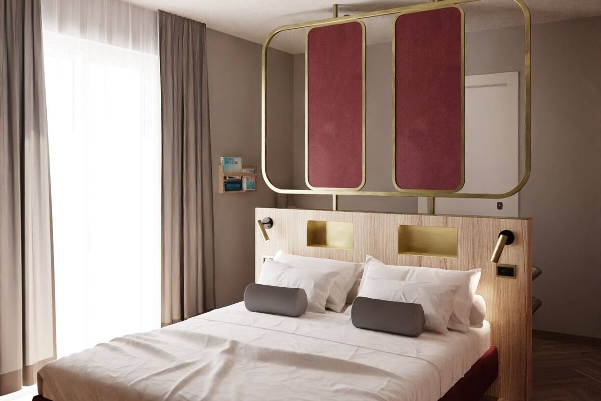 Una habitación de hotel moderna con una cama grande, un cabecero de madera y un amplio ventanal con cortinas.