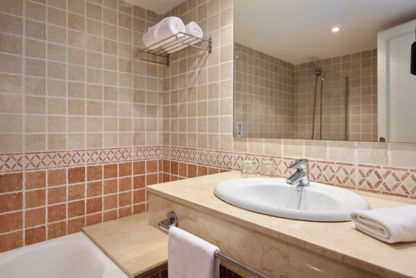 A bathroom with a white sink, a towel rack with two towels, a shower area, and a mirror.