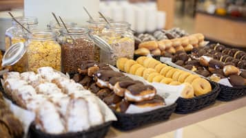 Un bufé con diversas opciones de comida, incluyendo cereales, pasteles y donas.