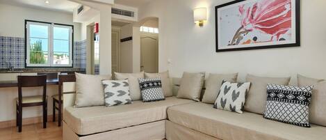Un salon comprenant un canapé, une table basse et un coin repas avec une chaise.