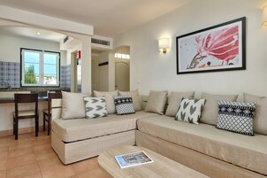Una sala de estar con un sofá, una mesa de centro y un comedor con una silla.
