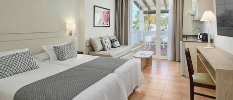 A hotel room with a bed, a sofa, a desk, and a view of the outdoors.