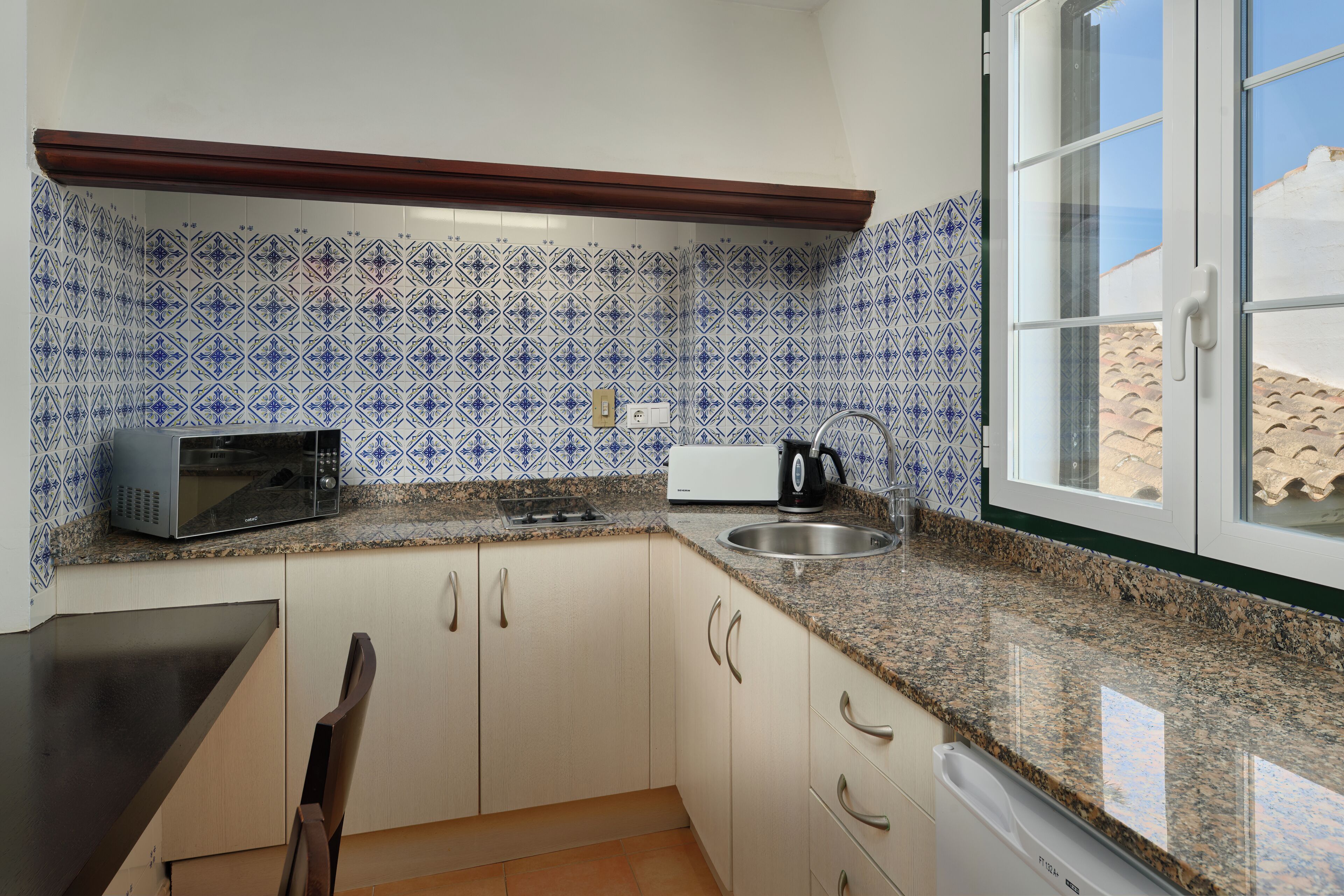 A compact kitchen with a microwave, kettle, and sink.