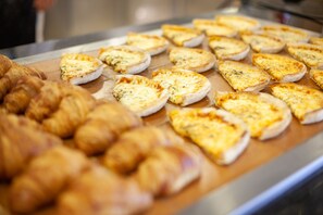 A variety of baked goods, including croissants and cheese-topped flatbreads, displayed on a metal tray. - Grupotel Club Menorca (Ciutadella de Menorca)