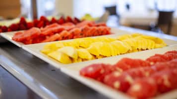 A buffet with various fruits including watermelon, mango, and tomatoes.