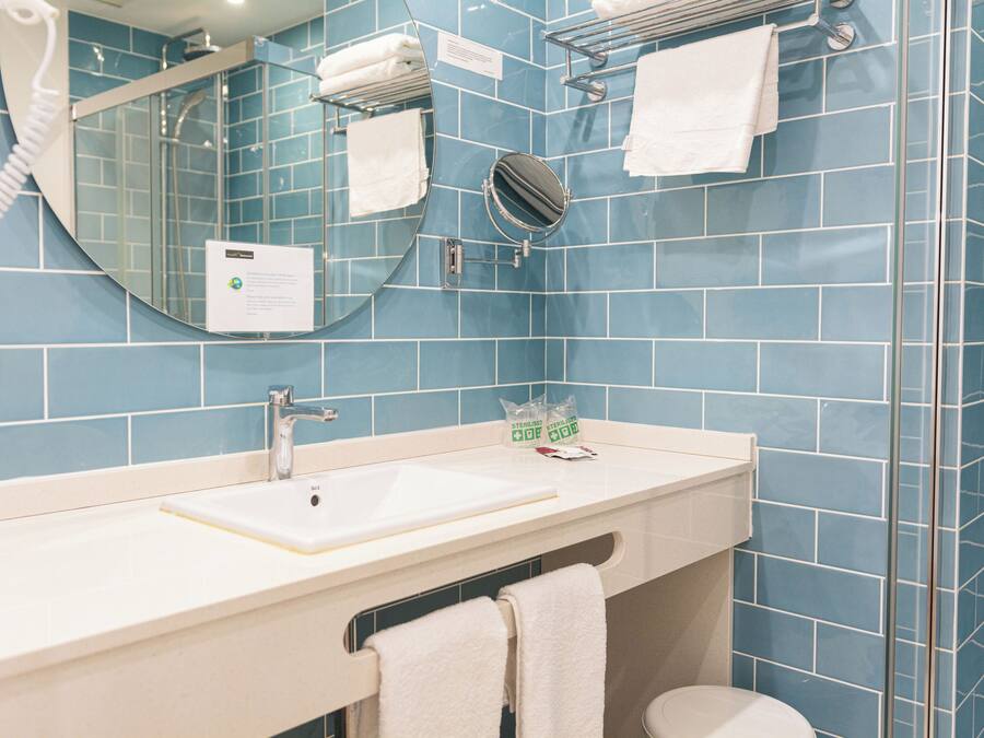 A bathroom with a sink, mirror, and towel rack.