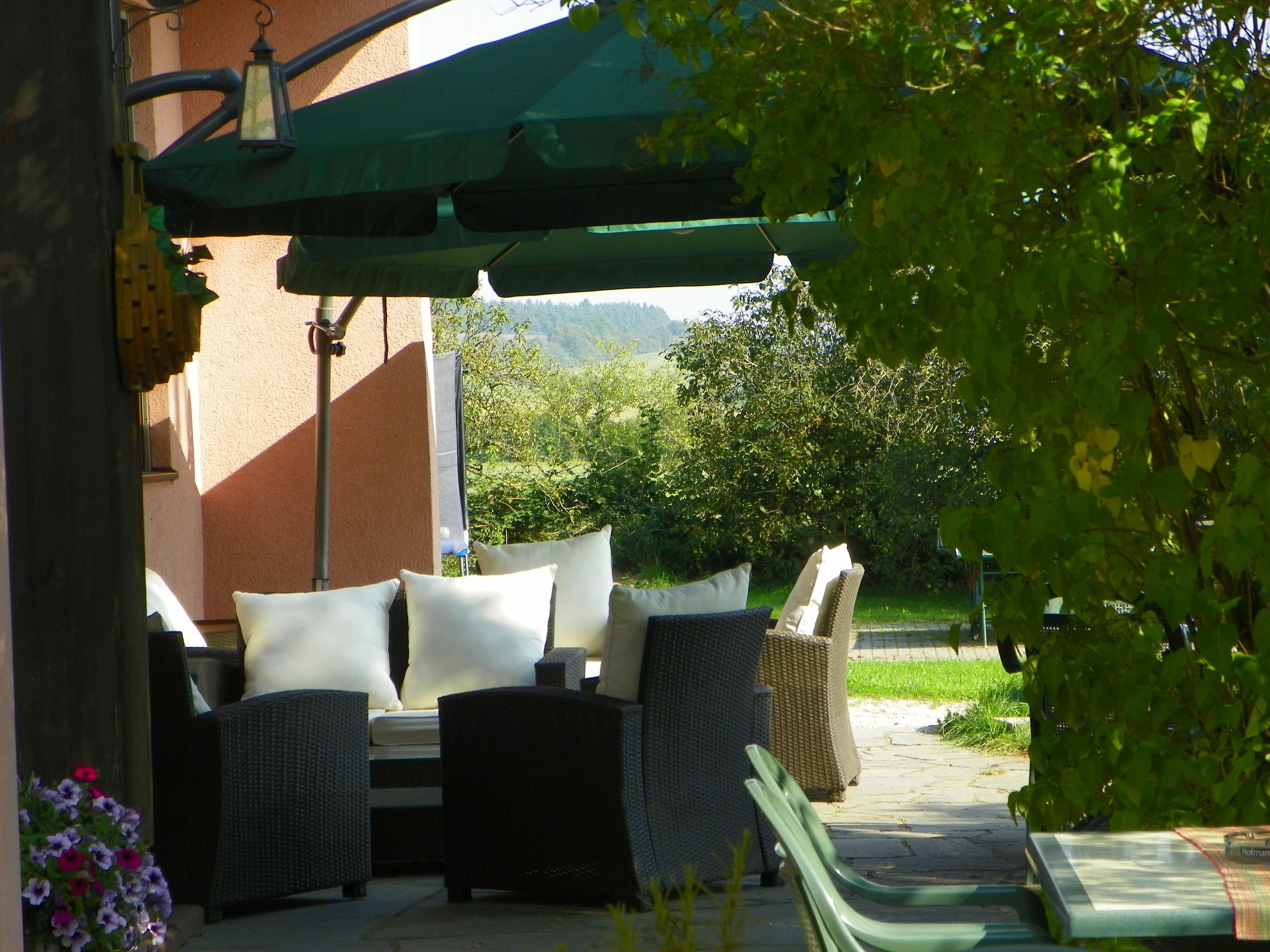 An outdoor seating area with wicker furniture and a green umbrella.