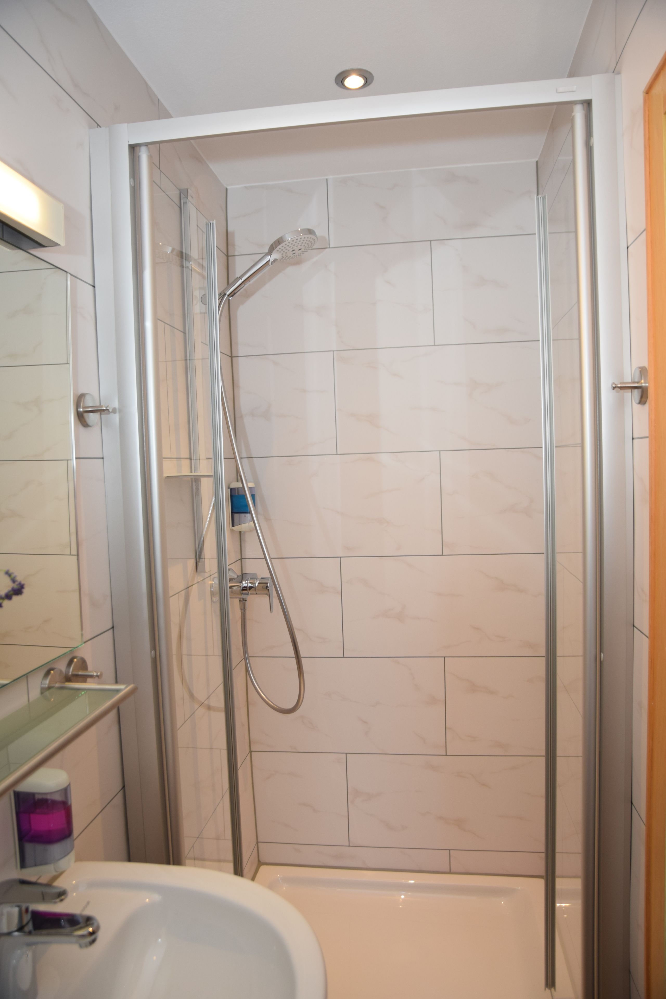 Un baño moderno con ducha acristalada, lavabo blanco y espejo.