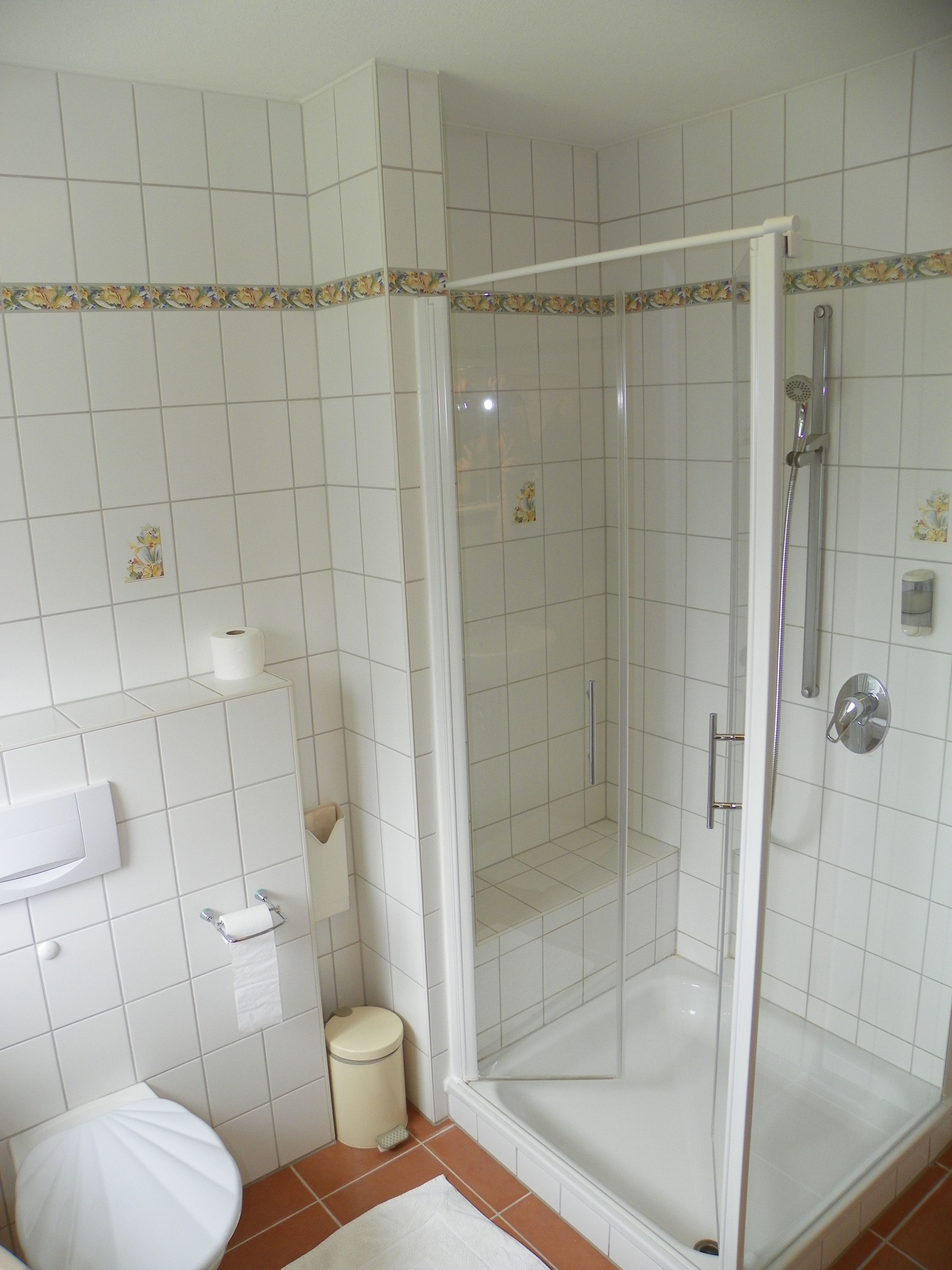 Un baño con ducha, inodoro y toallero.