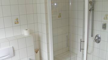 Un baño con ducha, inodoro y toallero.