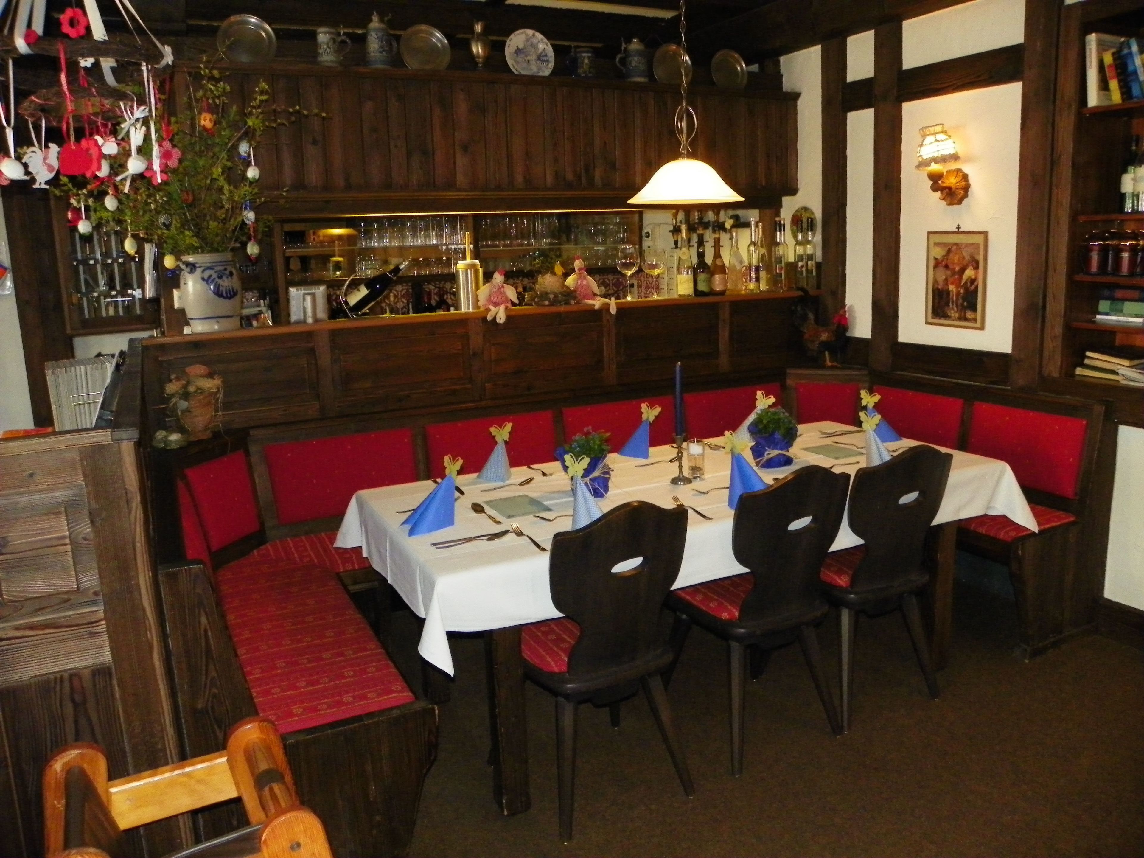 A restaurant with wooden booths, a bar area, and a white table set for dining.