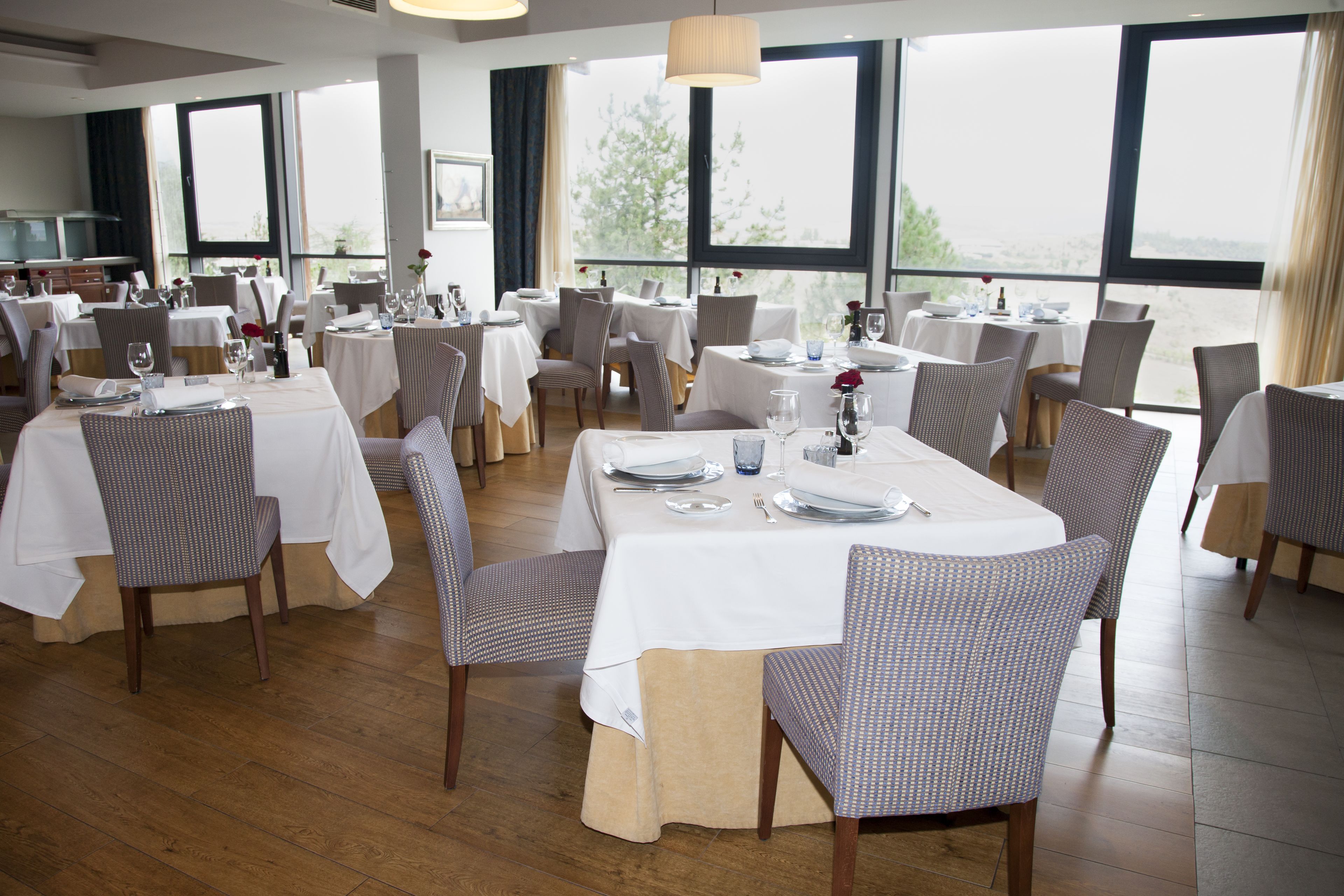 A restaurant with multiple tables set for dining, large windows offering a view, and a clean, modern interior.