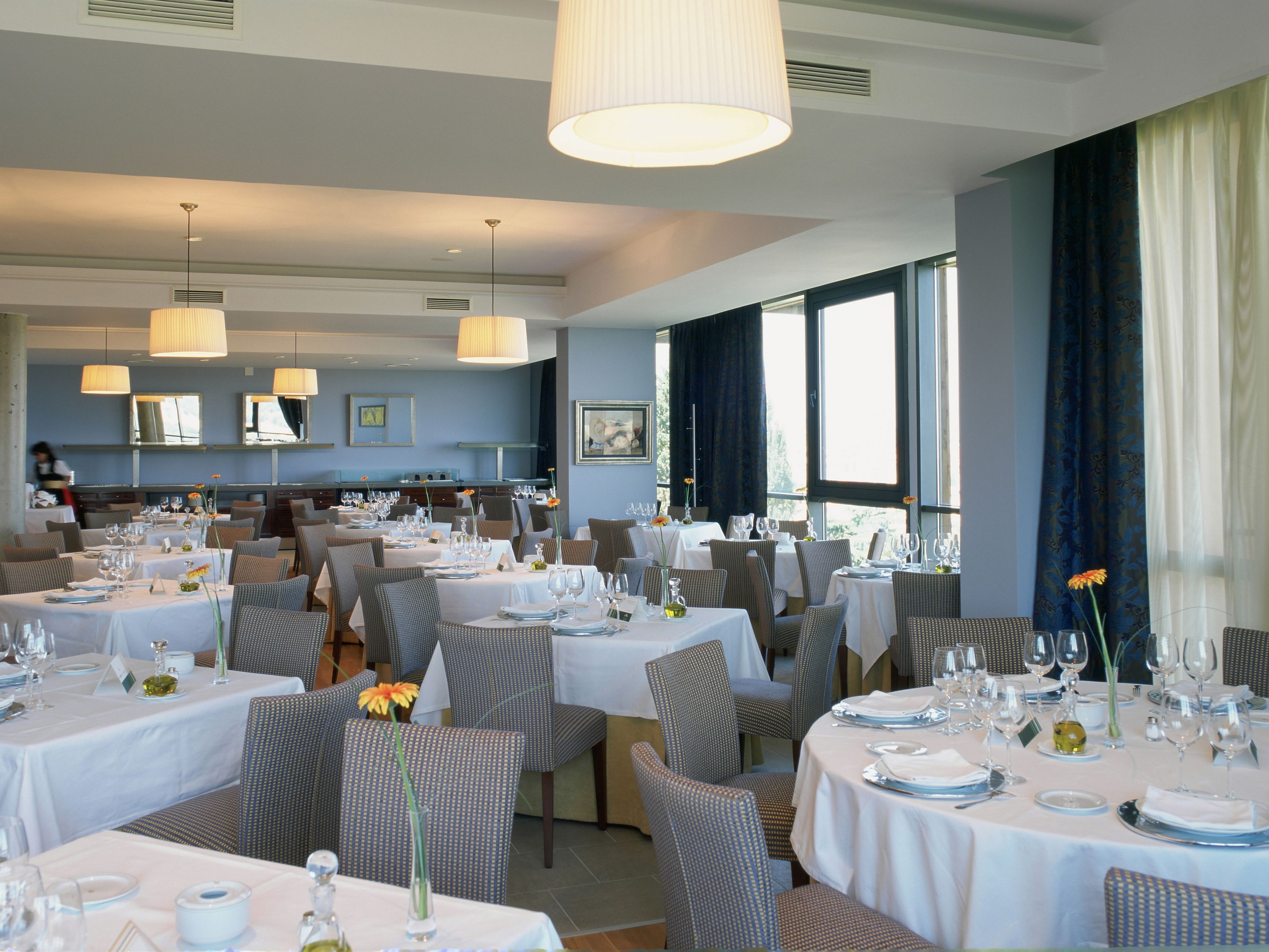 Een restaurant met meerdere eettafels, stoelen en hangende lampen.