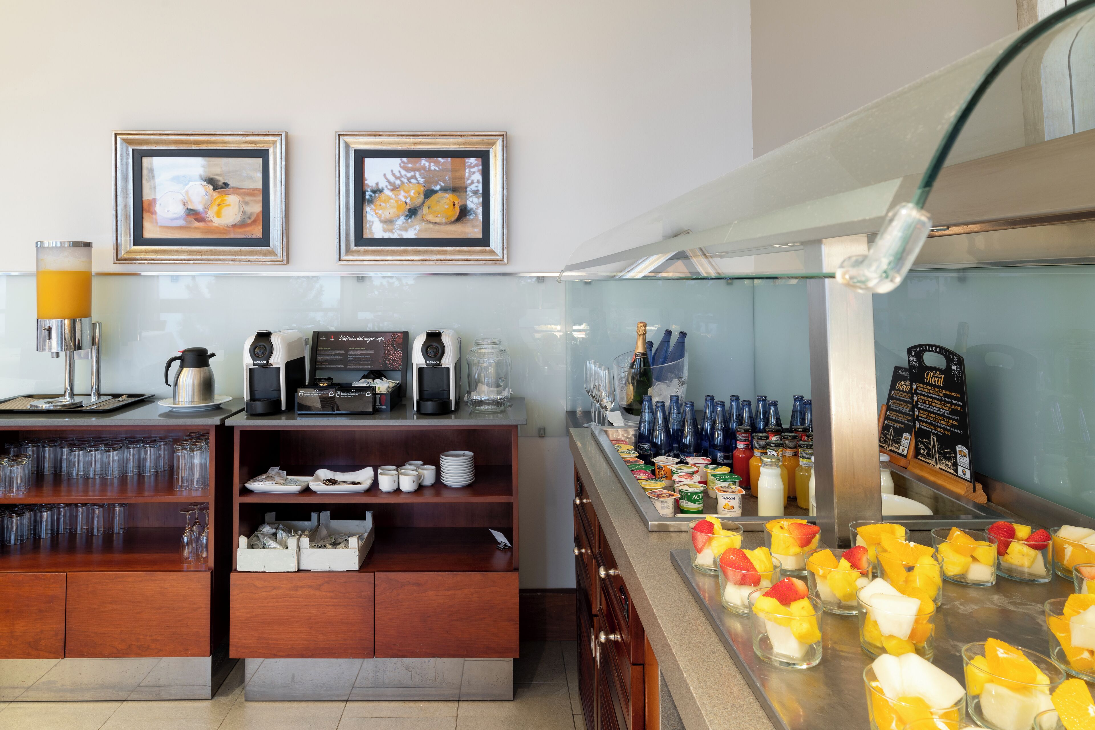A breakfast bar with coffee machines, a juice dispenser, and a variety of breakfast items.