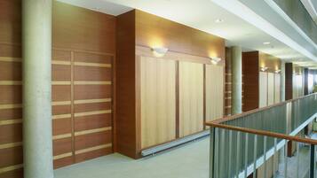 A modern interior with wooden panel walls, a concrete column, and a glass railing.