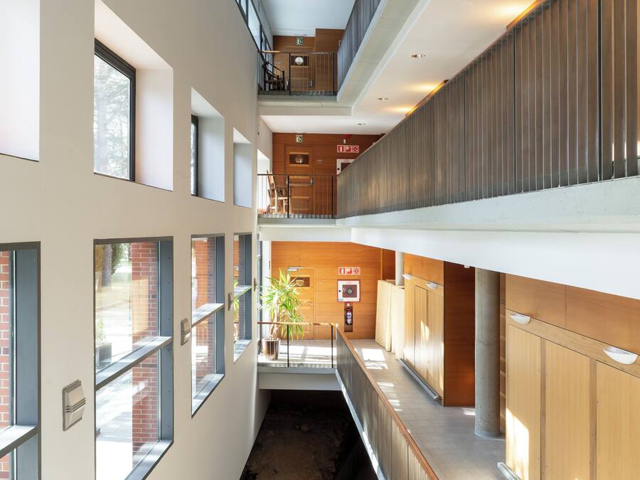 Un interior de varios niveles con un espacio central abierto, paneles de madera y una escalera.