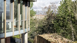 Un edificio moderno con ventanas amplias y un muro de contención de piedra.