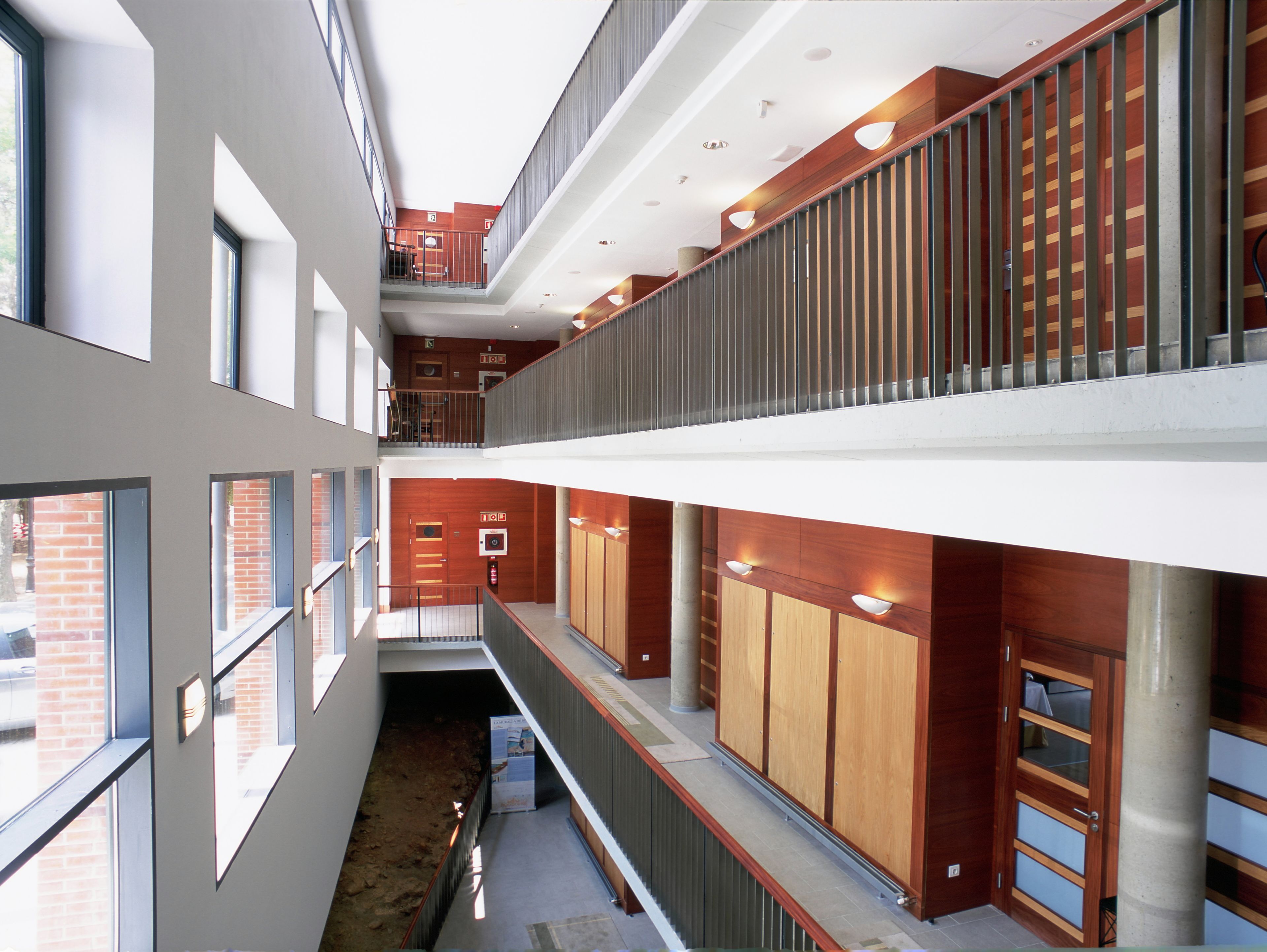 A multi-level interior with a central open space, wooden paneling, and a mezzanine level.