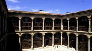 A courtyard with a central fountain, surrounded by multiple arches and columns, under a clear blue sky.