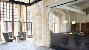 Un vestíbulo con paredes de piedra, ventanas amplias y dos sillones grises.