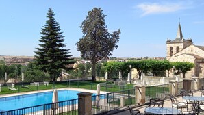 Zona de piscina con vistas a una iglesia y vegetación circundante.