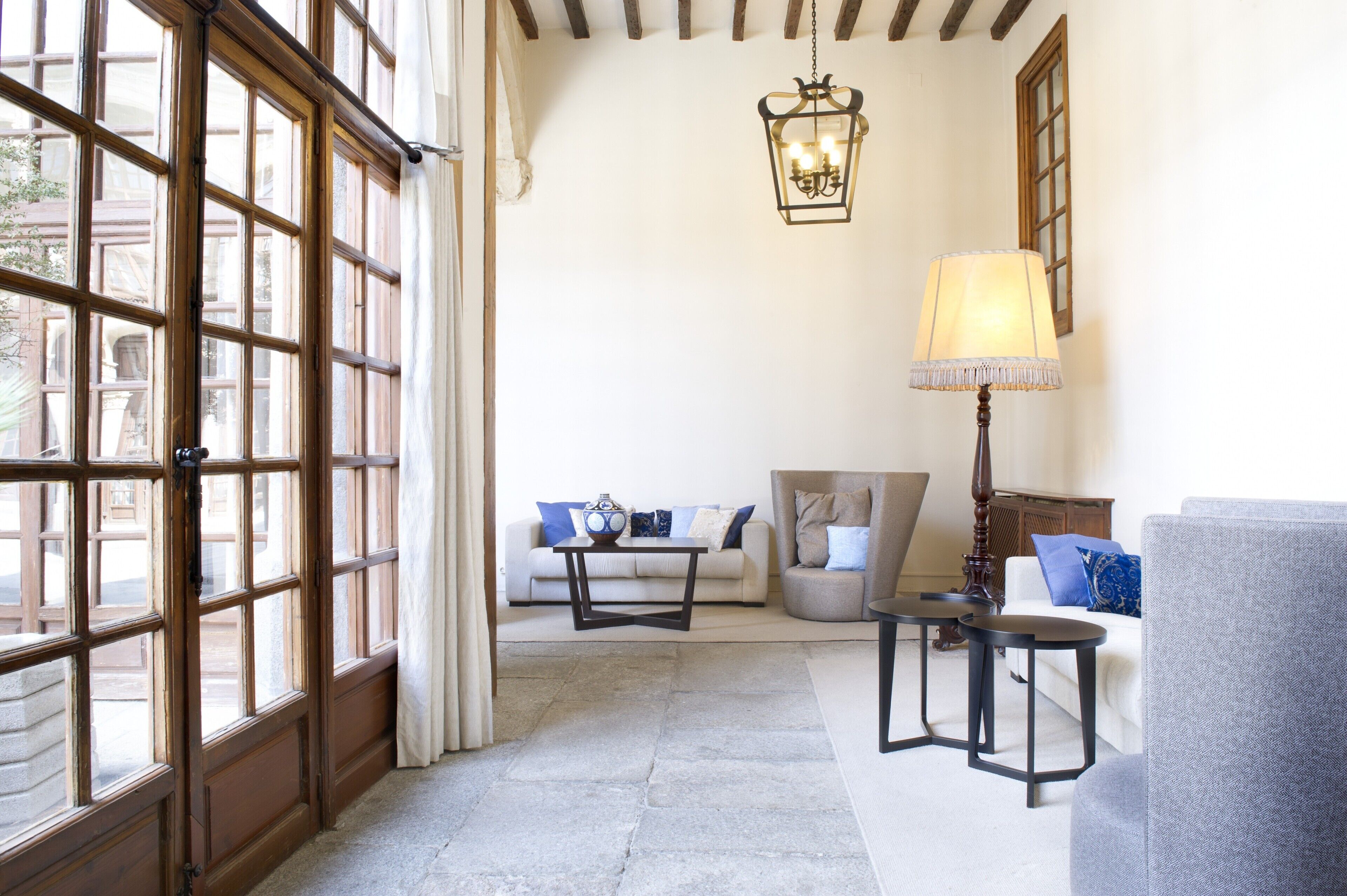 A room with a large window, a sofa, a coffee table, a lamp, and a chair.