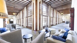 Un vestíbulo amplio con techos altos, ventanas grandes y una variedad de zonas de estar con sofás y sillones.
