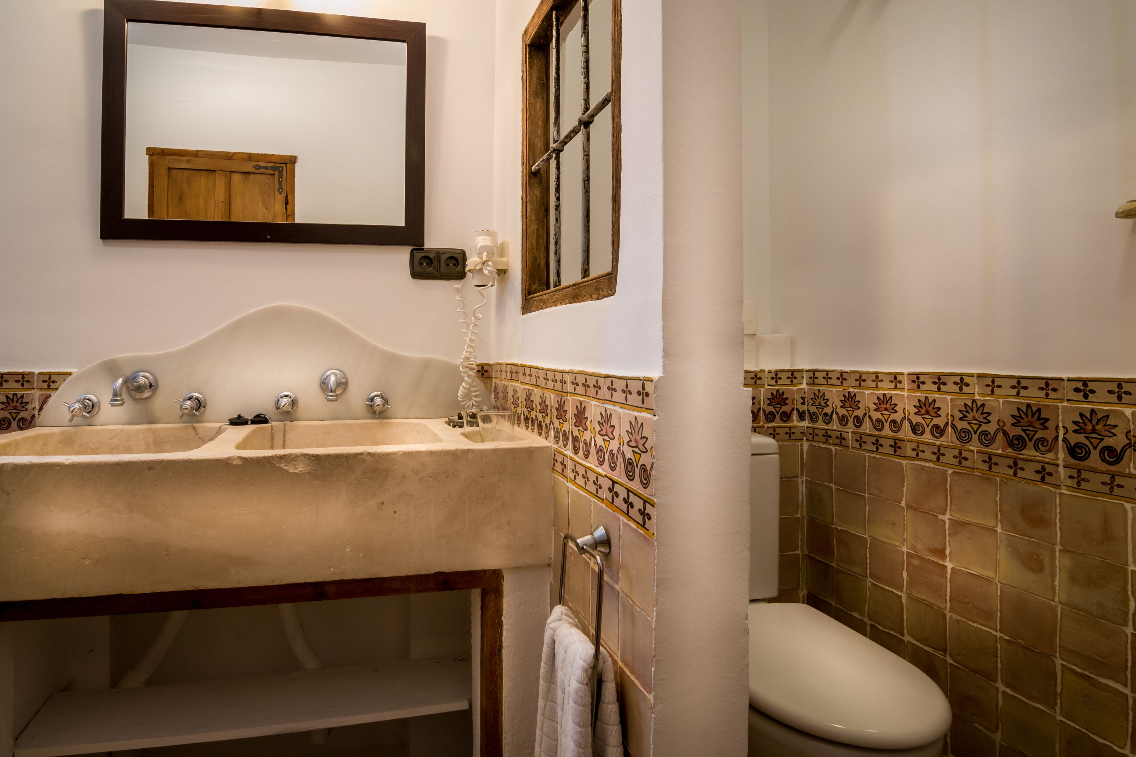 Un baño con lavamanos, espejo e inodoro.