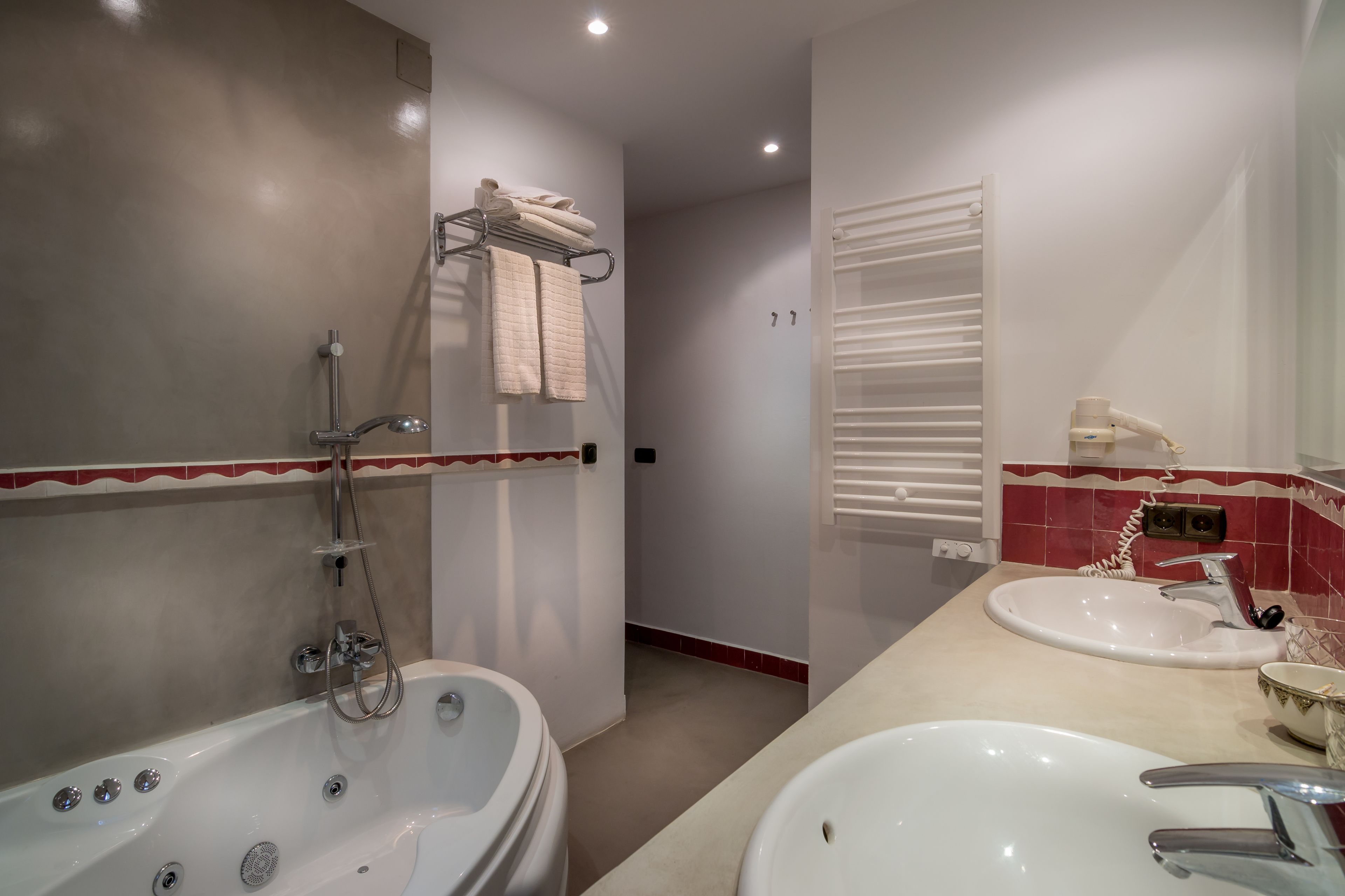 Une salle de bain moderne avec une baignoire, deux lavabos et un porte-serviettes.