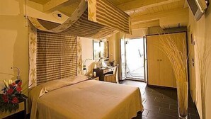 A bedroom with a bed, a desk, a chair, and a door leading to another room. - Hotel Cavalluccio Marino (Gabicce Mare)