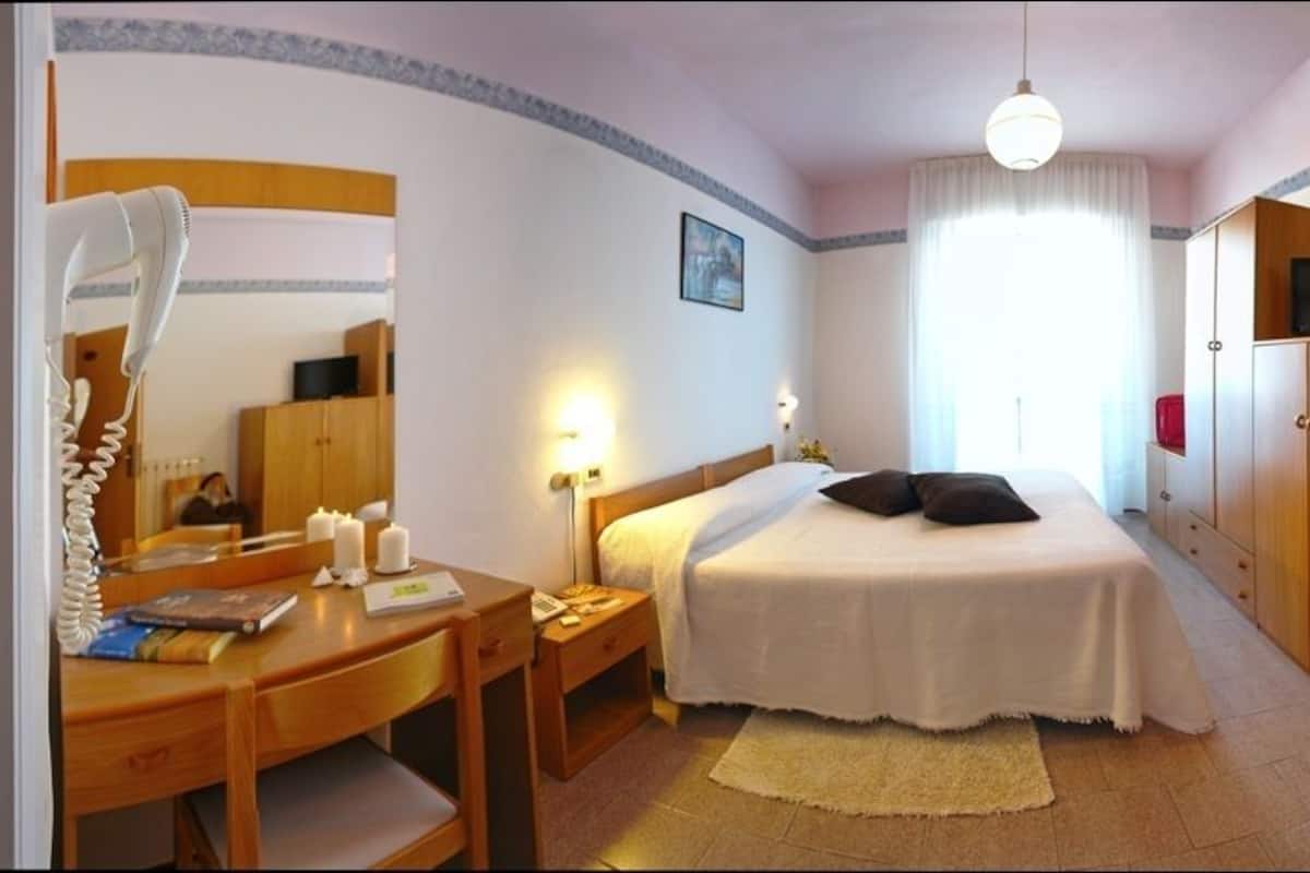 Ein Schlafzimmer mit Bett, Schreibtisch, Stuhl, Kleiderschrank und Fernseher.