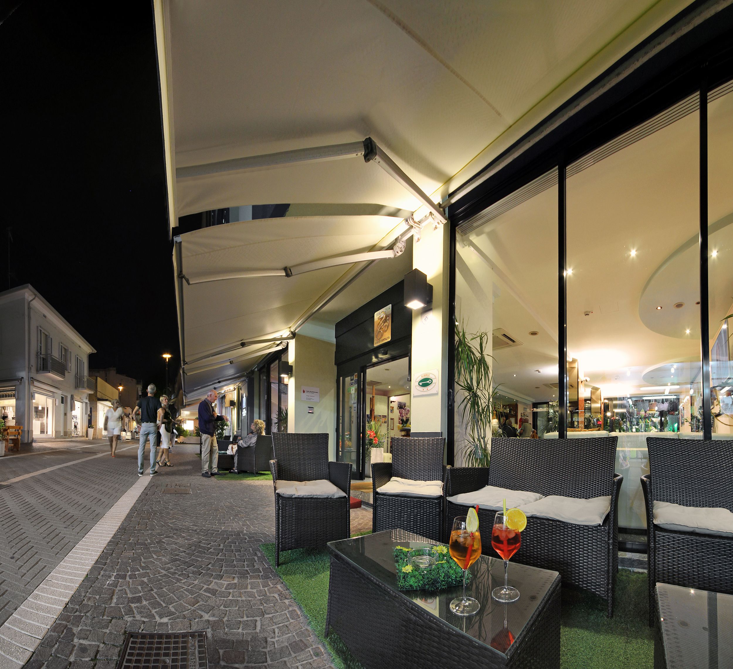 An outdoor seating area with wicker furniture and a glass table with drinks.