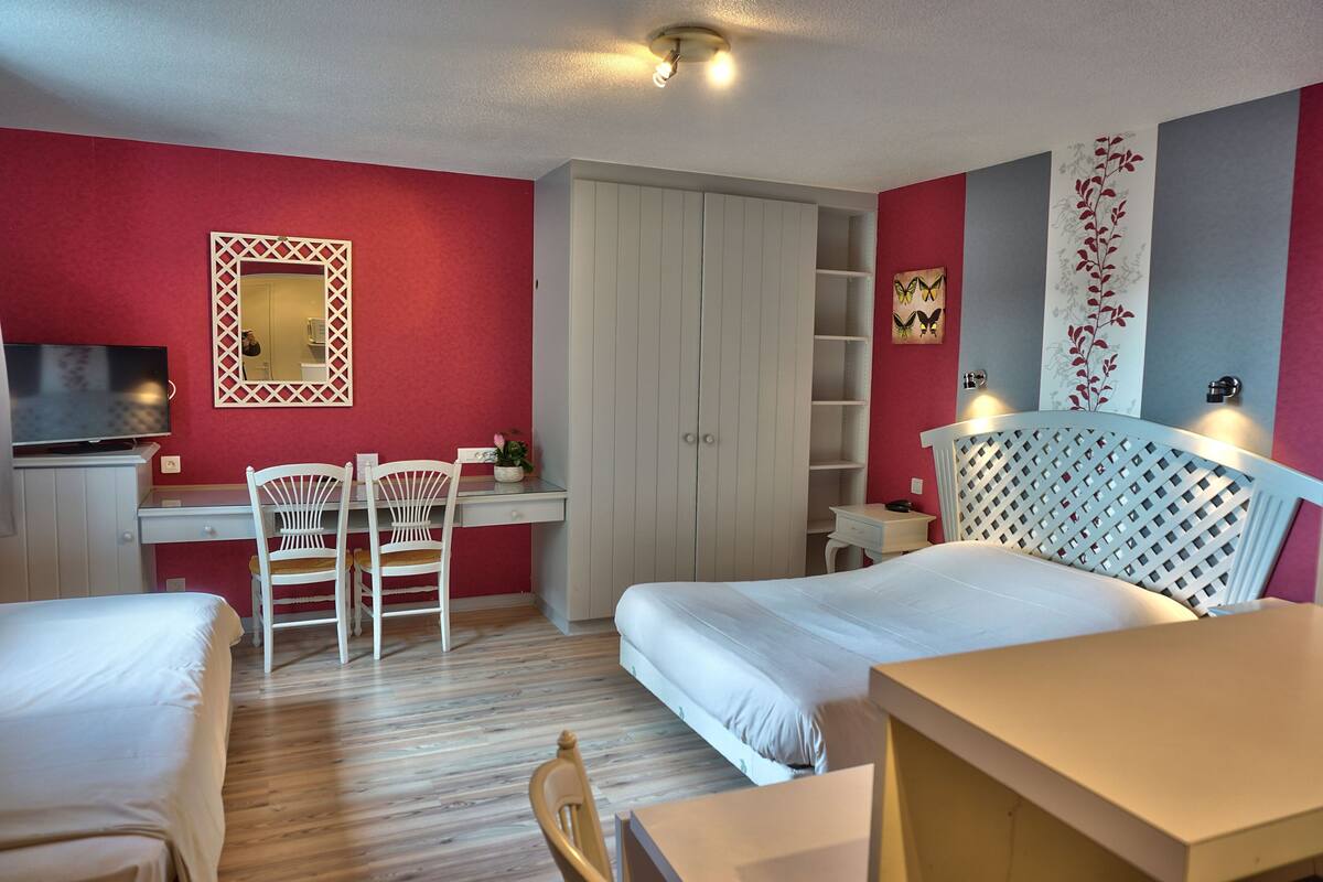 Ein Hotelzimmer mit Bett, Schreibtisch mit Stuhl, Kleiderschrank und Fernseher.