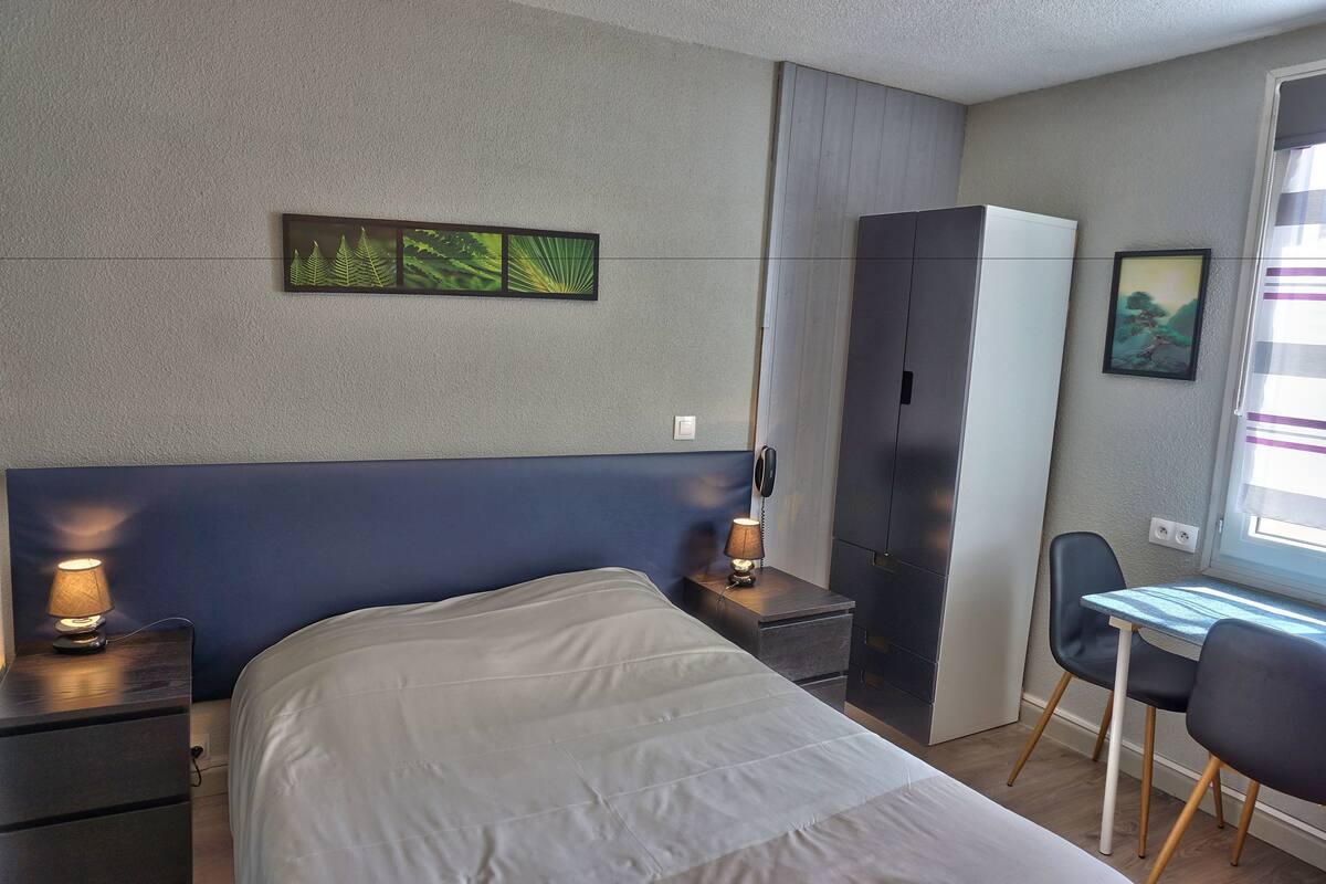 Ein Schlafzimmer mit einem Bett, Nachttischen, einem Schreibtisch und Stühlen.