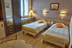 A hotel room with two beds, a desk, a chair, a wardrobe, and a window. - Le Bellevue (Caen)