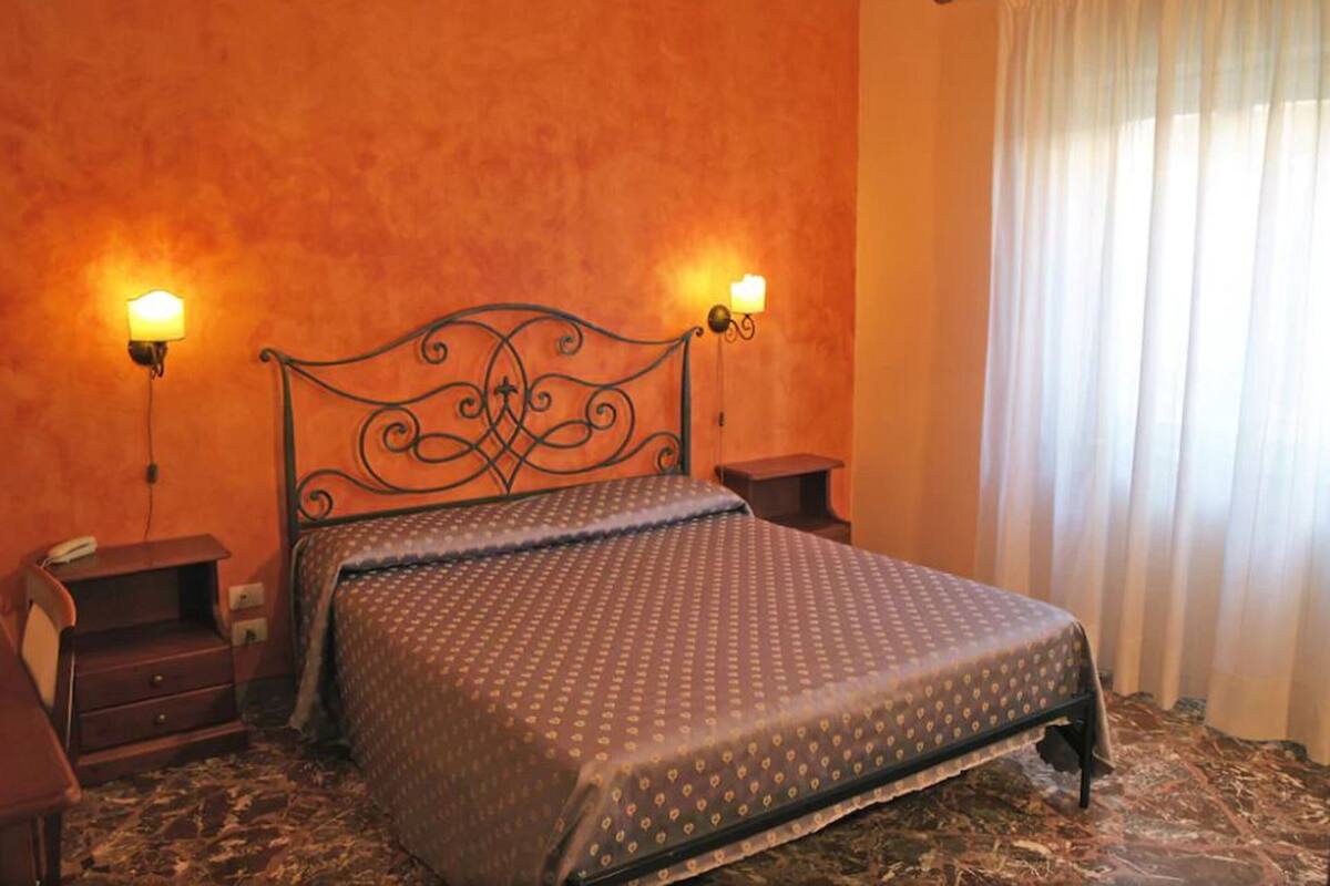 Un dormitorio con una cama, dos mesitas de noche y una cortina.