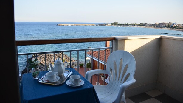 A balcony with a table set for two, overlooking a coastal view. - Hotel Costa Azzurra (Giardini Naxos)