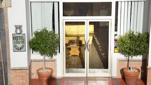 A hotel entrance with a glass door, two potted plants, and a sign reading "HOTEL COSTA AZUL". - Hotel Costa Azzurra (Giardini Naxos)