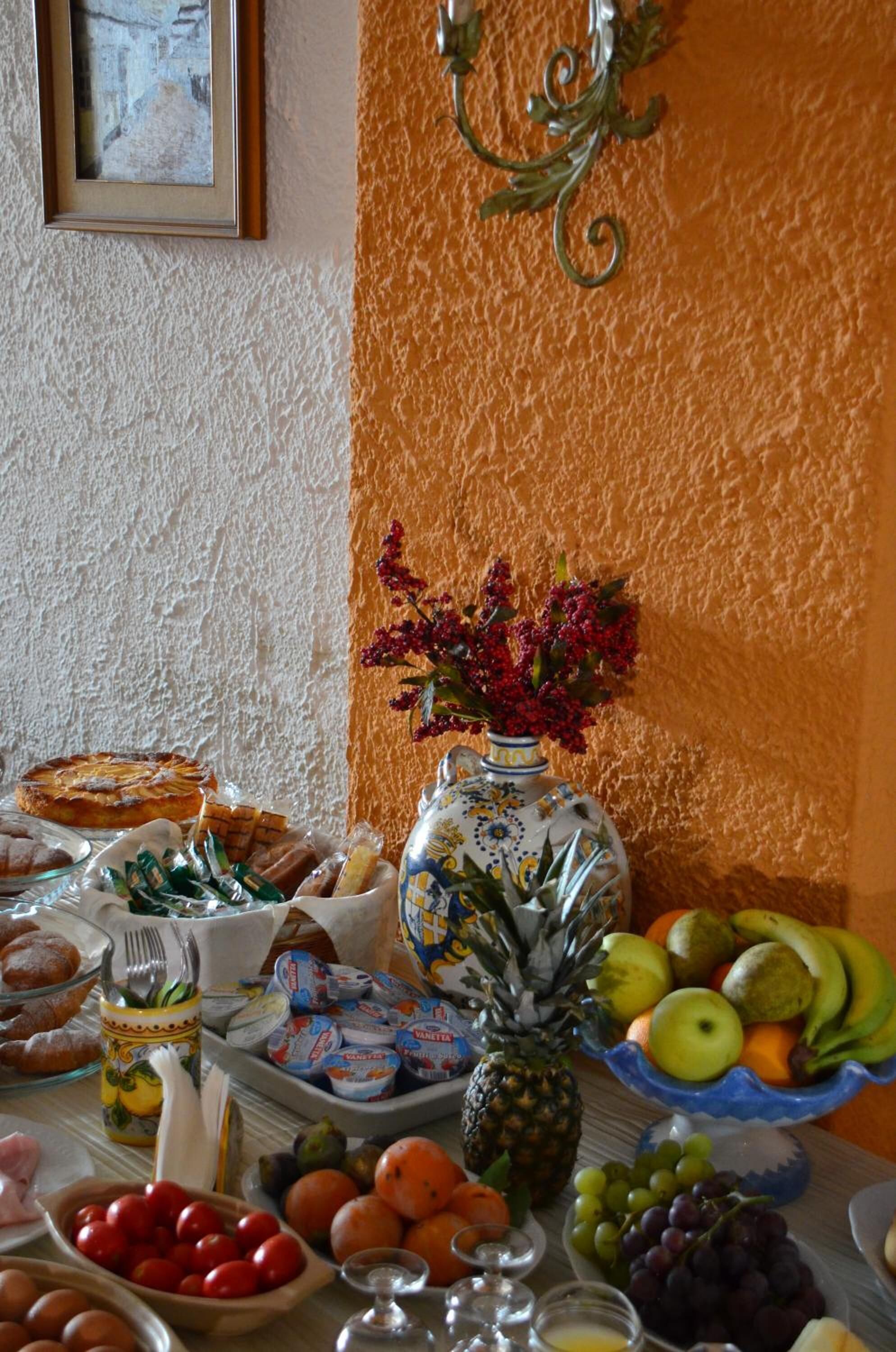 Ein Buffet mit verschiedenen Speisen, eine Vase mit Blumen und ein gerahmtes Bild an der Wand.