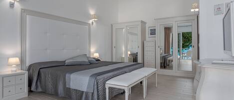 Un dormitorio con cama, mesitas de noche, un banco, un armario y un espejo.