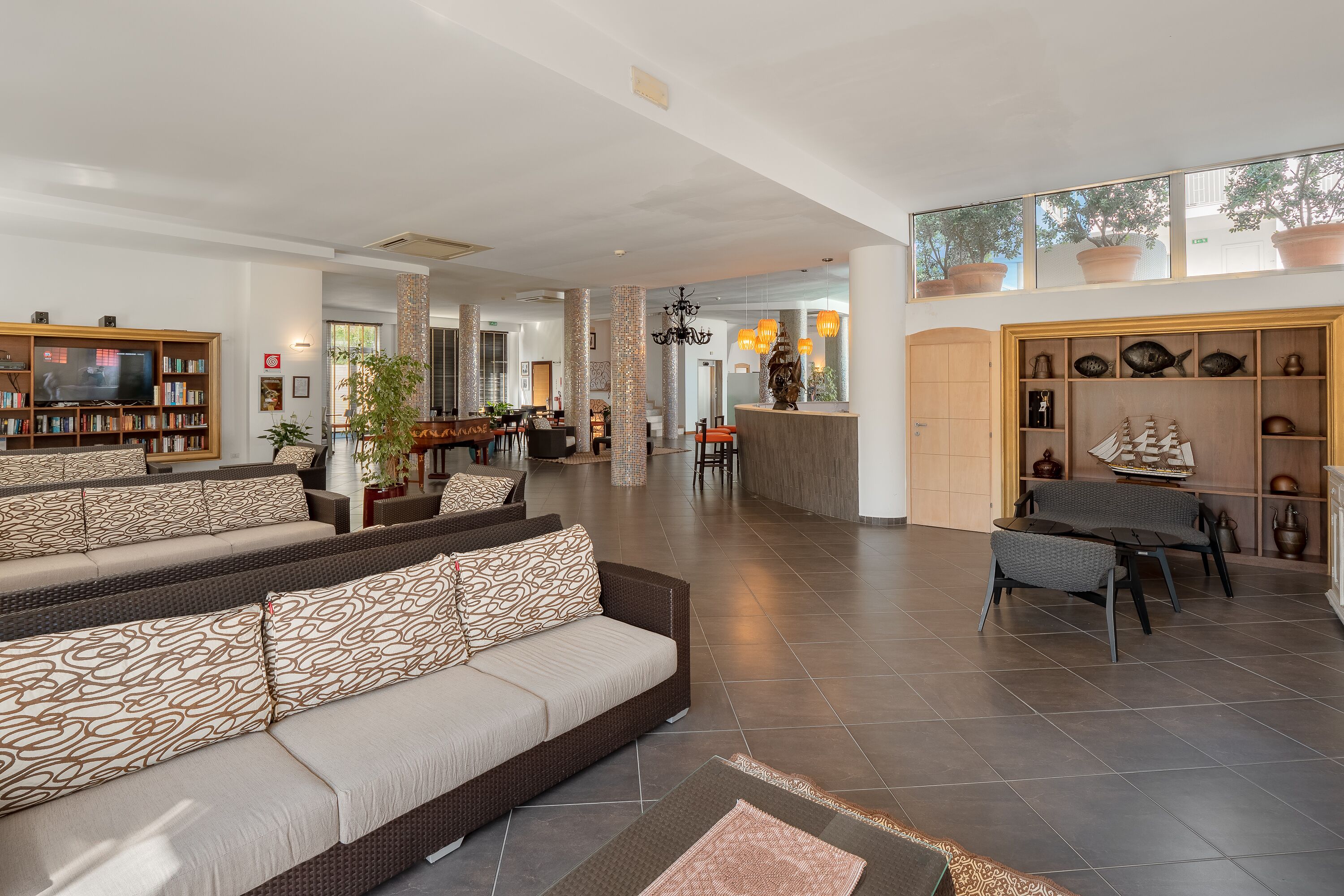 A spacious living area with a large sofa, a television, and a bookshelf.
